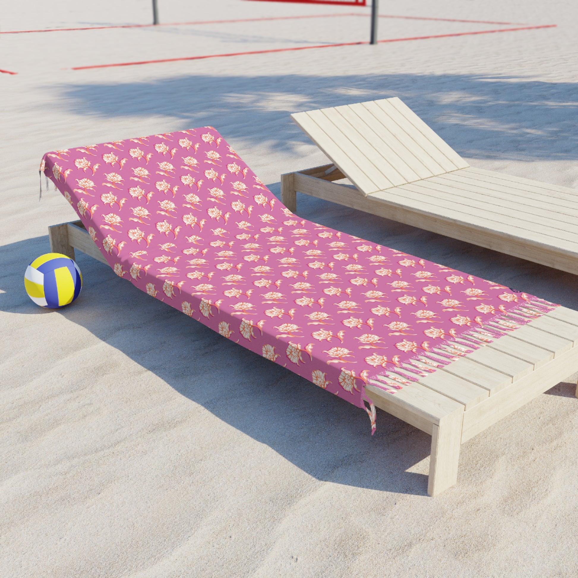 Side  View of Watercolor Woodblock Beach Towel with Tassels on a beach lying across beach lounger by volleyball net in Peony Pink Color Option