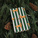 Green and Pink and White striped wrapping paper featuring a dog illustration wrapped gift with brown bow laying on a Pine Tree