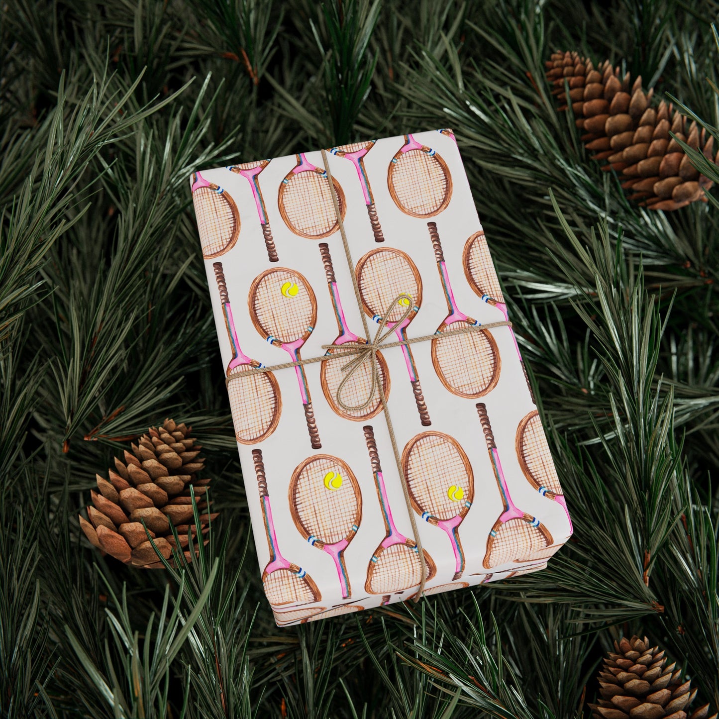 Topspin Tennis Wrapping Paper wrapped around a gift box sitting on a pine tree in Peony Pink Color chocie
