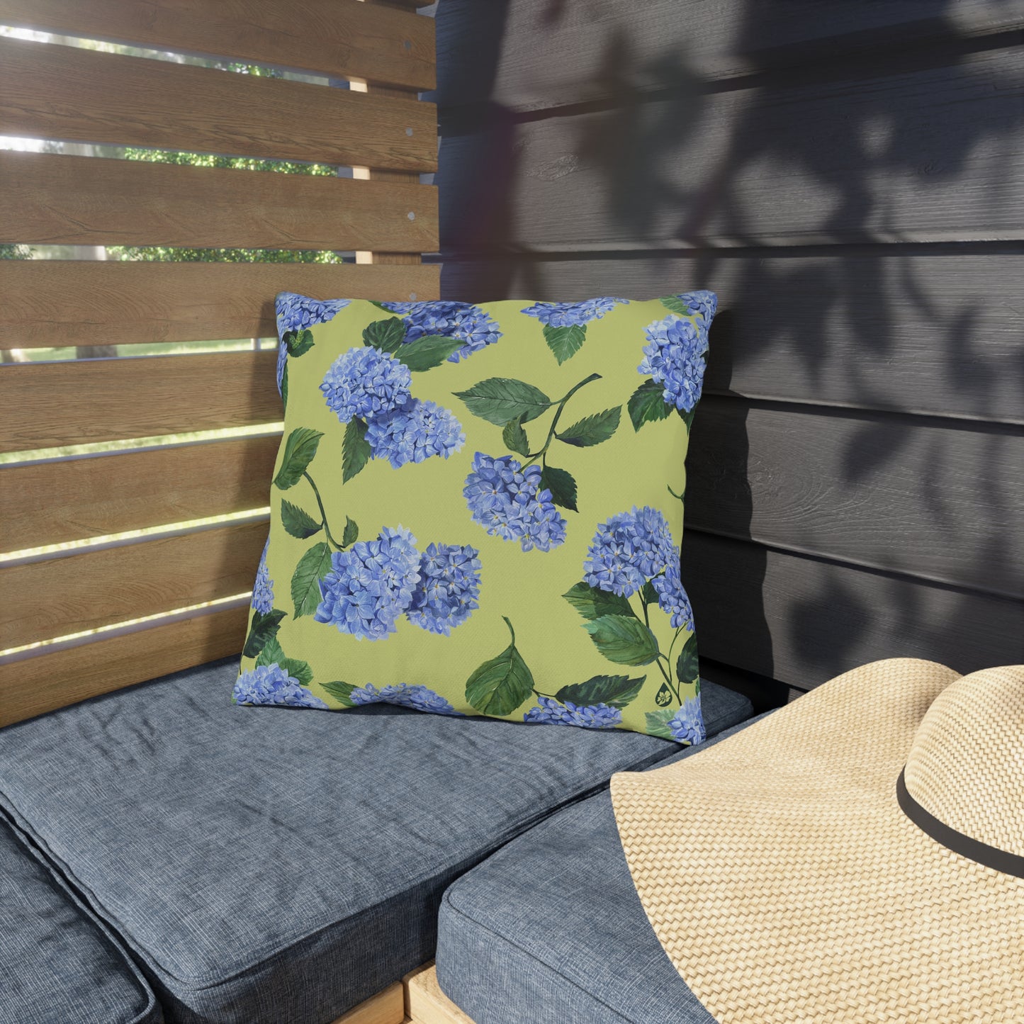 Hydrangea Patterned Outdoor Pillow in Honeydew on porch bench next to beach hat
