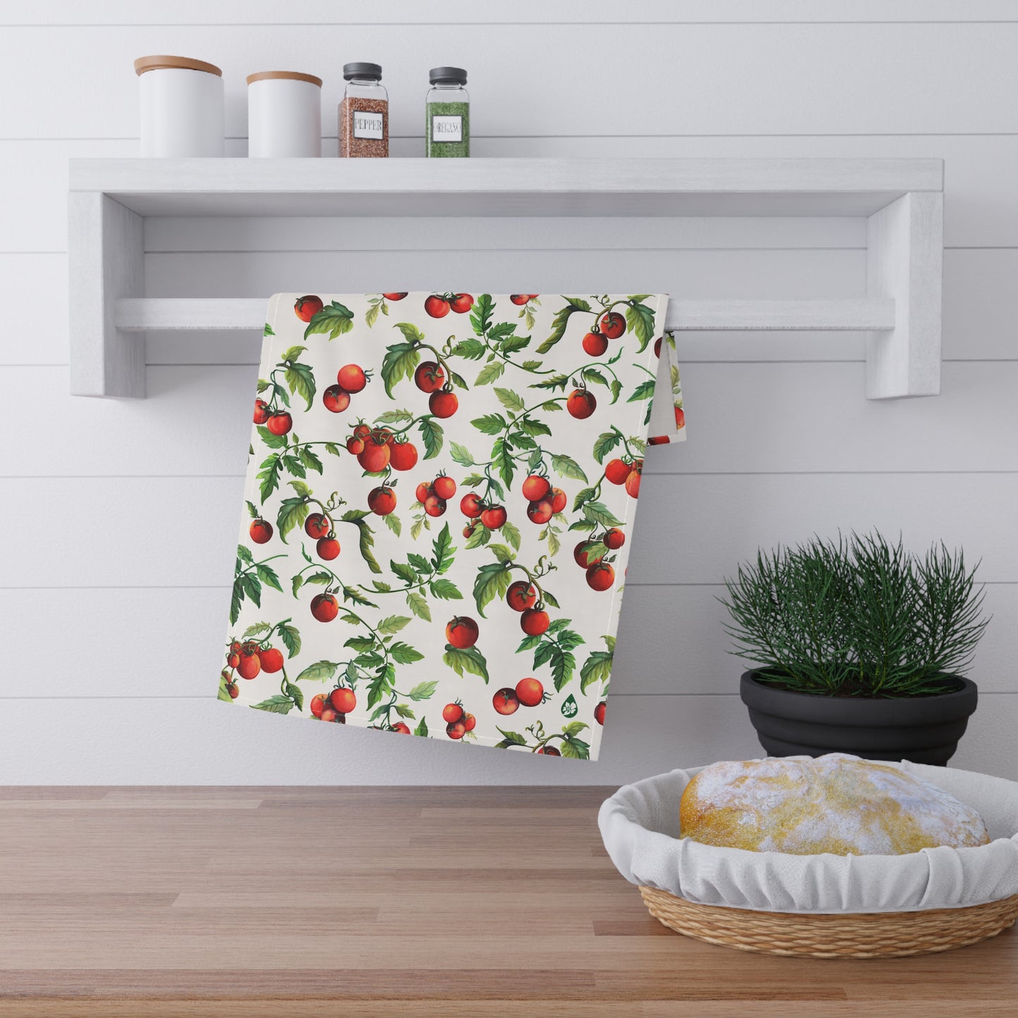 View of Tomato Tomato Kitchen towel hanging on spice rack railing over counter with sourdough bread and plant