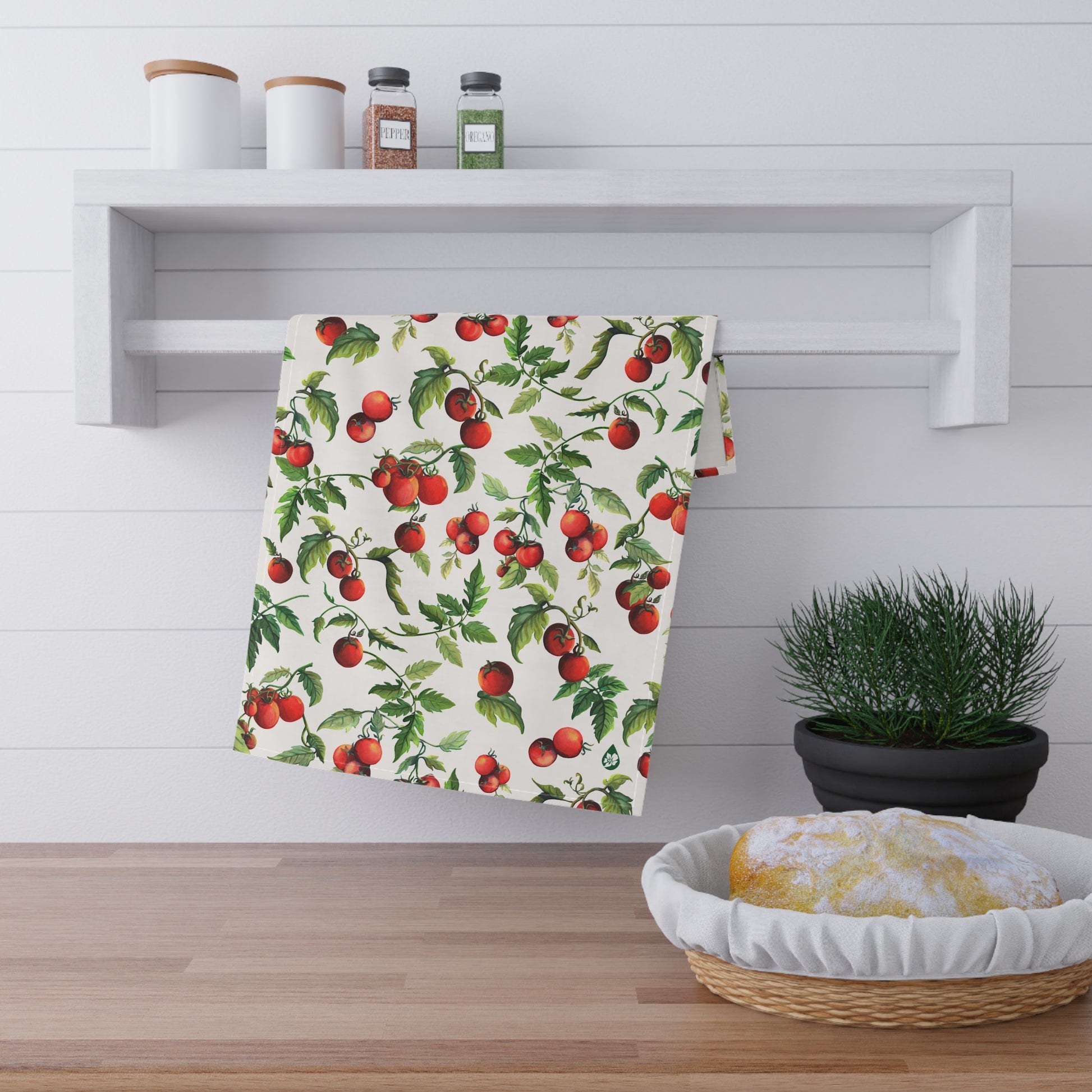 View of Tomato Tomato Kitchen towel hanging on spice rack railing over counter with sourdough bread and plant