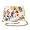A rectangular clutch bag with a gold chain strap, featuring a light pink textured background decorated with orange orchids and colorful butterflies.