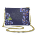 A blue leather crossbody purse with a gold-plated chain strap, adorned with a floral pattern of violets and leaves.