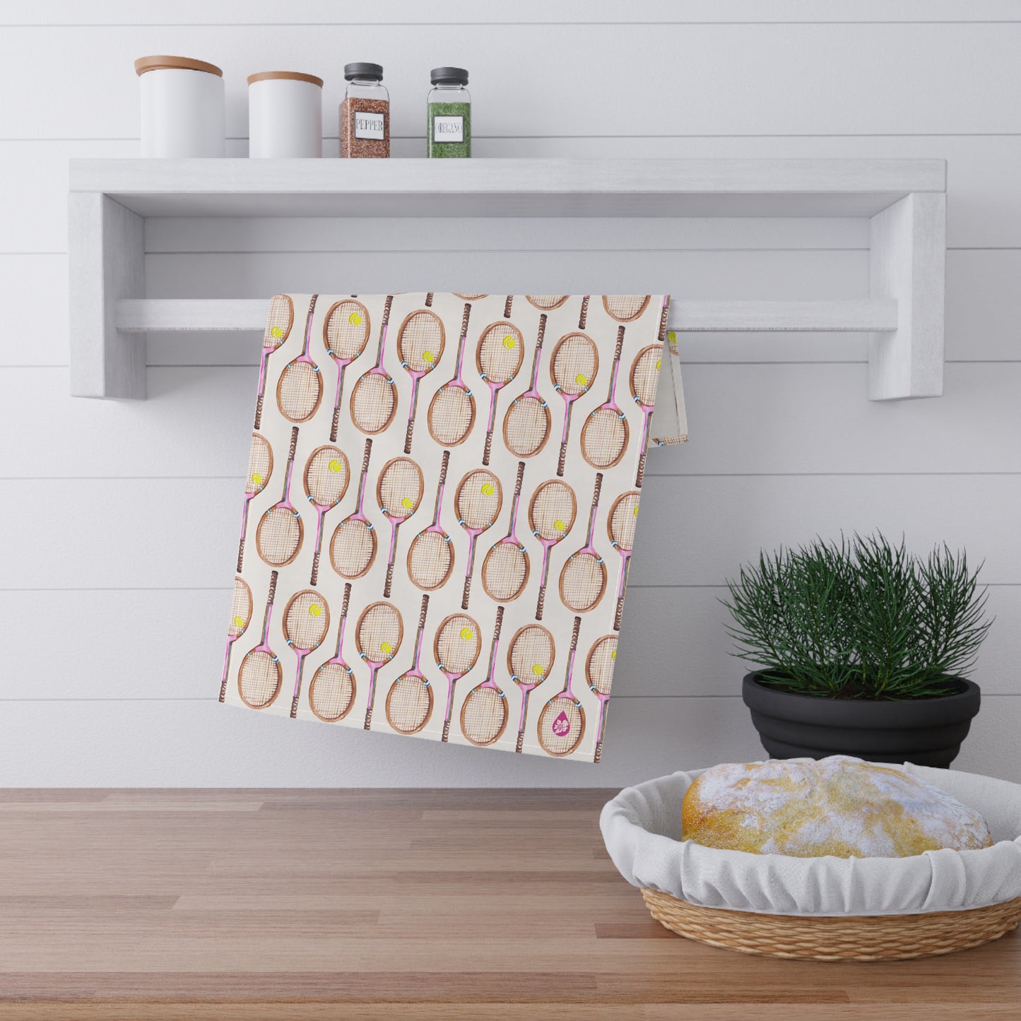 Topspin Tennis print kitchen towel in pink hanging on railing over kitchen counter next to sourdough bread and plant
