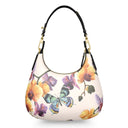A curved shoulder bag with a cream-colored pebbled leather base, decorated with a vibrant print of yellow flowers, purple orchids, and a blue and yellow butterfly. It features a black leather shoulder strap with gold-tone hardware.