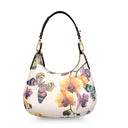 A curved shoulder bag with a cream-colored pebbled leather base, decorated with a vibrant print of orchid flowers and multicolored butterflies. It features a black leather shoulder strap with gold-tone hardware.