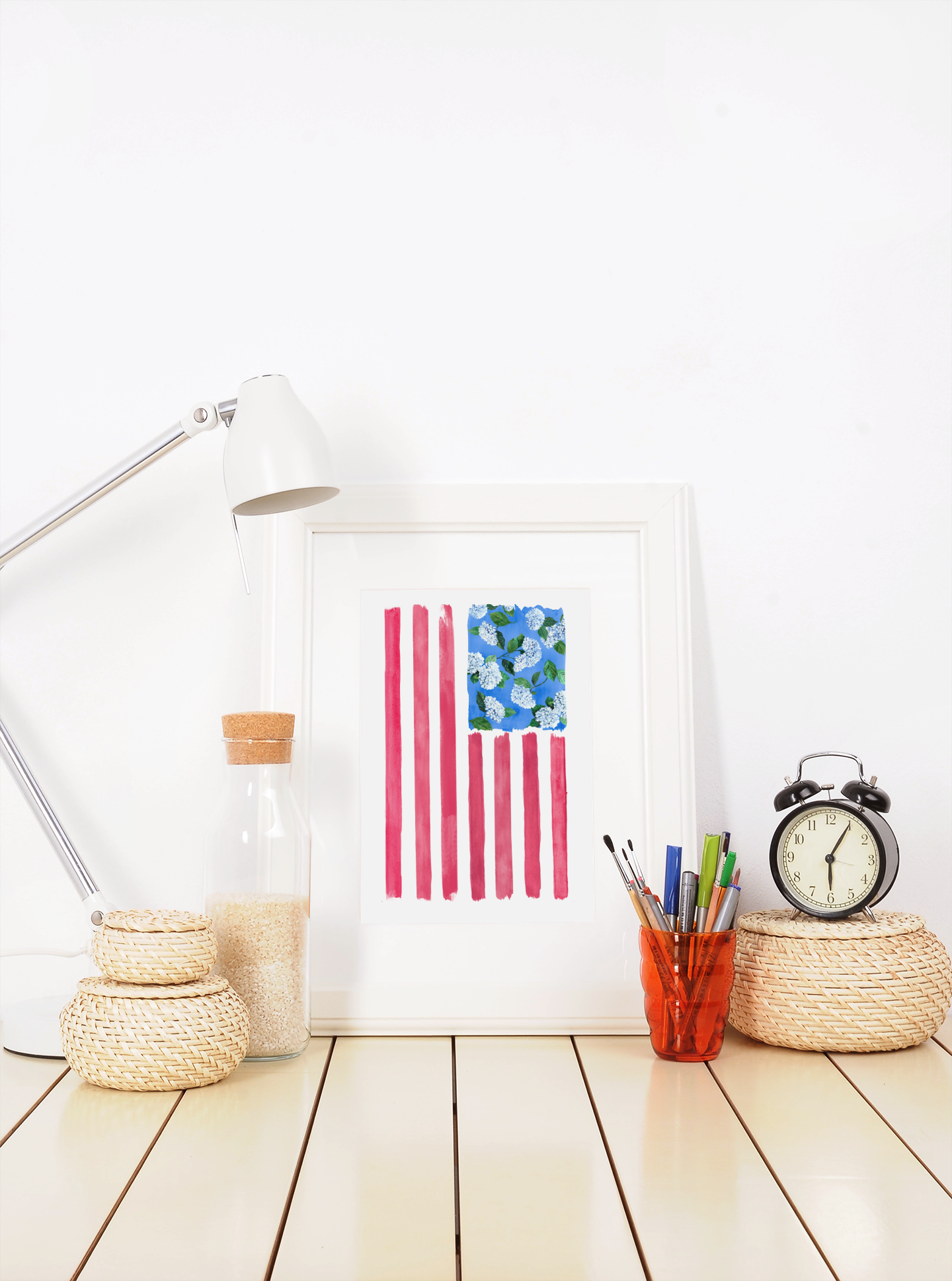 Liberty print shown in white frame on desk with architect lamp and desk supplies
