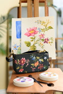 Pigment and Petal Midnight Bloom Purse in front of original artwork sitting on an art easel
